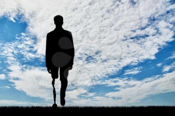concept of rehabilitation of invalids with prosthetic legs. Walking silhouette of a disabled man on sky background
