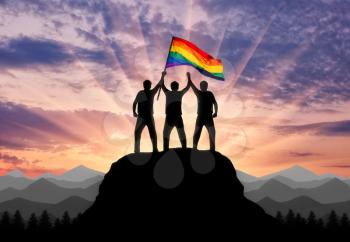Silhouette of a group of gay men with a rainbow flag on a mountain top. Concept rights and freedoms of gays