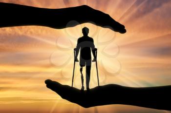 Concept of aid and care for disabled with a prosthetic leg. Disabled person with a prosthetic leg with crutches, in hands of man
