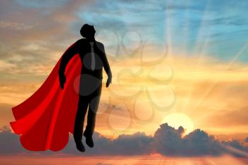 Superman businessman superhero. Silhouette of a businessman in the image of a superman flies in the sky at sunset