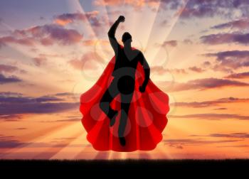 Superman businessman superhero. Silhouette of a businessman in the image of a superman flies in the sky at sunset