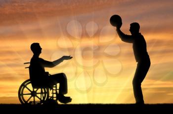 Silhouette of a disabled man in a wheelchair catches a ball from a friend on a sunset background. The concept of fun pastime for people with disabilities with friends