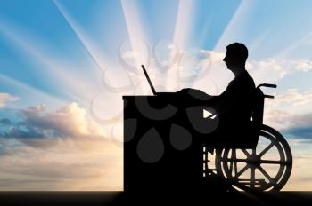 A disabled employee in a wheelchair working with a laptop at the table. The concept of employment of persons with disabilities