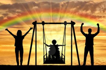 Silhouette of happy child is disabled in a wheelchair on an adaptive swing with mom and dad on the background of a sea sunset with a rainbow. The concept of lifestyle of children with disabilities and their support