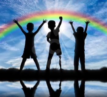 Children with disabilities and friendship with them concept. Happy disabled boy with a prosthetic leg standing among their friends, near the river and the rainbow