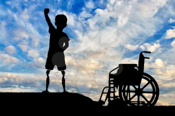 Children with disabilities concept. Happy disabled boy with a prosthetic legs standing near a wheelchair against the sky
