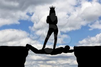 Selfish woman with a crown standing on a man in the form of a bridge over an abyss. Concept of selfishness in business
