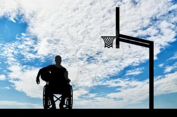 Silhouette of a disabled basketball player in a wheelchair holding the ball in his hand. The concept of disabled athletes