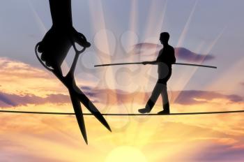 Silhouette of a businessman walking on a tightrope balances and a hand with scissors intends to cut the rope. The concept of meanness in business