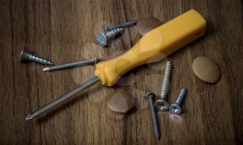 Screwdriver and screws on a wooden background.