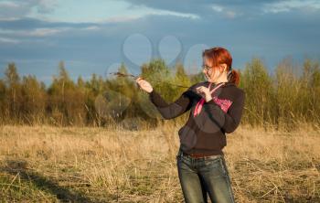 Girl standing in a field and considers stem horse chestnut.