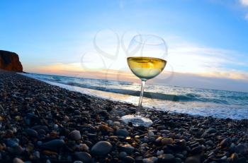 Romantic glass of wine sitting on the beach at sunset 