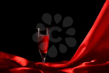 Glass of wine on red silk with dark background