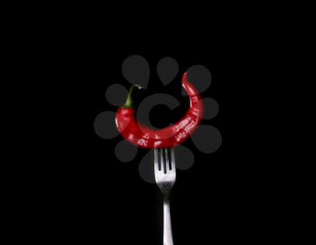 Paper chili on fork on black background