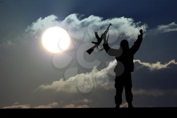 Silhouette of military soldier or officer with weapons at sunset. shot, holding gun, colorful sky, Concept of a terrorist. Silhouette terrorists with rifle at sunset