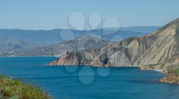 Beautiful green slopes of the mountains by the sea. Bright colors of the sky, the sea and greenery. Crimea, East coast