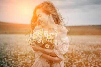 Beautiful young girl with curly red hair in chamomile field. Concept and idea of a healthy lifestyle, skin and hair care