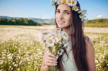 Beautiful girl in daisy field. Summer sunset. happy young lady and spring-green nature, harmony concept. Carefree happy brunette woman with healthy wavy hair having fun outdoor in nature.