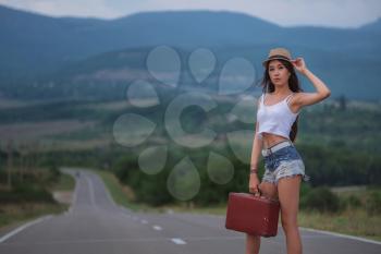 women is hailing a car on a road. Thumbing a ride. Outdoors vacation. Asian