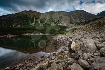 Man Traveler with backpack near mountain lake . Travel Lifestyle concept. Travel and active life concept with team. Adventure and travel in the mountains region in the Poland Tatri