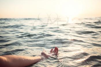 Woman hands in water inviting you over sunset golden rays. Summer vacation and travel concept