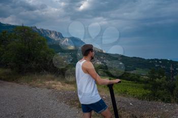 Young man riding an electric scooter on mountain range. enjoying fresh air and beautiful scenic views. Ecological transportation concept