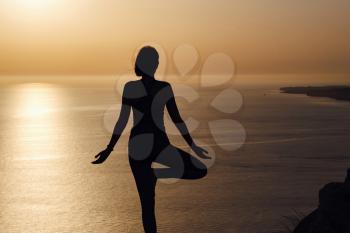 The woman with yoga posture on the mountain at sunset Silhouette of gorgeous young woman practicing yoga outdoor. wellness, healthcare, sport and lifestyle concept