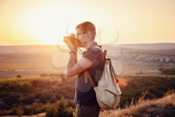 Man photographer with backpack and camera taking photo of sunset mountains Travel Lifestyle hobby concept adventure active vacations outdoor