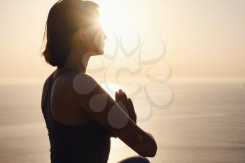 Young woman practicing yoga over sunset sea. meditation in the lotus position. Yoga silhouette. Harmony and meditation concept. Healthy lifestyle