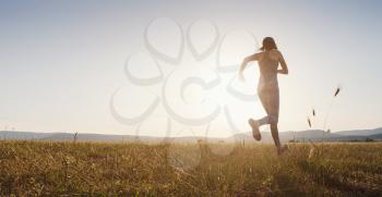 Jogging woman running in summer field at sunset. woman fitness silhouette sunrise jogging workout wellness concept.