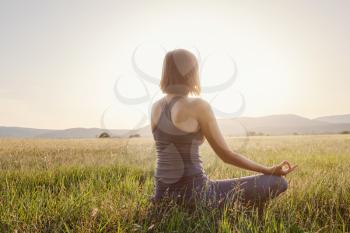 woman practices yoga and meditates in the lotus position on the field. Healthy lifestyle and Yoga concept.