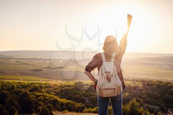Happy woman stands with raised hands on background of sunset in mountain's range. young tourist woman enjoys the scenery in the mountains.