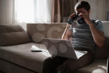 Funny man looking searching binoculars a laptop on the table working at home office. Job search online. searching idea and concept