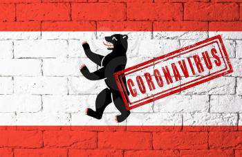 Flag of the regions of Germany Berlin with original proportions. stamped of Coronavirus. brick wall texture. Corona virus concept. On the verge of a COVID-19 or 2019-nCoV Pandemic.