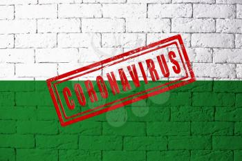 Flag of the regions of Germany Saxony with original proportions. stamped of Coronavirus. brick wall texture. Corona virus concept. On the verge of a COVID-19 or 2019-nCoV Pandemic.