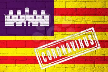 Flag of the regions or communities of Spain Balearic Islands original proportions. stamped of Coronavirus. brick wall texture. Corona virus concept. On the verge of a COVID-19 or 2019-nCoV Pandemic.