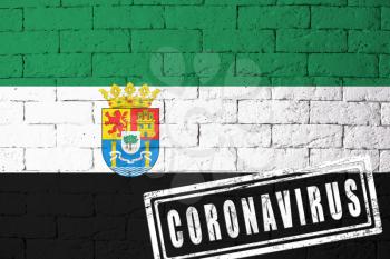 Flag of the regions or communities of Spain Extremadura with original proportions. stamped of Coronavirus. brick wall texture. Corona virus concept. On the verge of a COVID-19 or 2019-nCoV Pandemic.