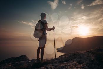 Man hiking at sunset mountains with heavy backpack. Travel Lifestyle wanderlust adventure concept summer vacations outdoor alone into the wild, mock up text.