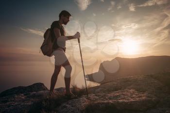 Man hiking at sunset mountains with heavy backpack. Travel Lifestyle wanderlust adventure concept summer vacations outdoor alone into the wild, mock up text.