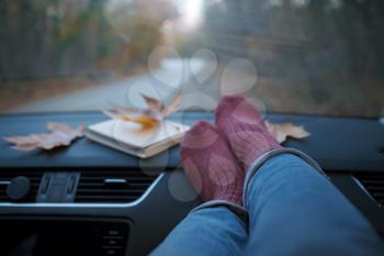 Woman feet in warm socks on car dashboard . The concept of freedom of movement. Autumn Weekend.