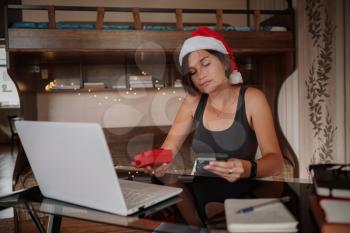 Attractive asian woman holding a credit card and shopping on a laptop. Christmas online shopping, sales and discounts promotions during holidays, online shopping at home and lockdown coronavirus.Xmas