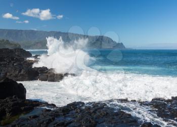 Waves crash into narrow gully that forms Queens Bath at Princeville, Kauai, Hawaii