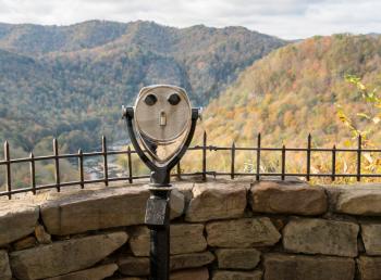 Rear view of coin operated binoculars or telescope in shape of a face at Hawks Nest State Park in fall colors