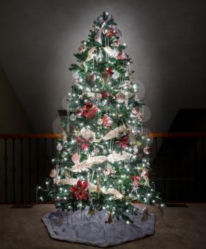 Ornate and decorated Christmas Tree on the upper balcony of a modern family home and illuminated by its own lights