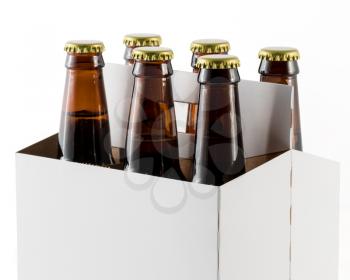 Six beer bottles in cardboard container with gold caps with corner of carrier facing camera