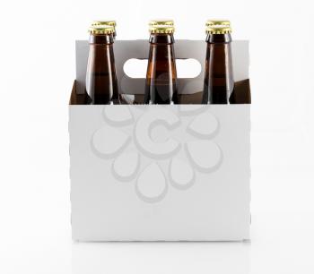 Six beer bottles in cardboard container with gold caps with side of carrier facing camera