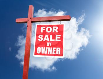 Realtor installed for sale by owner sign for house or real estate set against blue sky and clouds