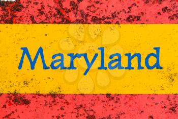 Detail of the word Maryland on a newspaper stand that is brightly painted but starting to rust