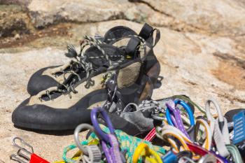 Close up of fawn and black climbing shoes ropes and carabiners on granite rock prior to climb
