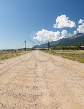 Long straight dirt graded road across open countryside to distant mountains in Colorado